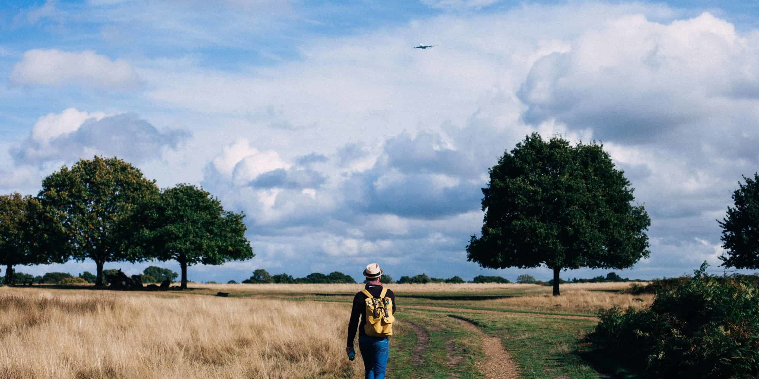 person-in-yellow-and-black-backpack-walking-on-green-grass-211047