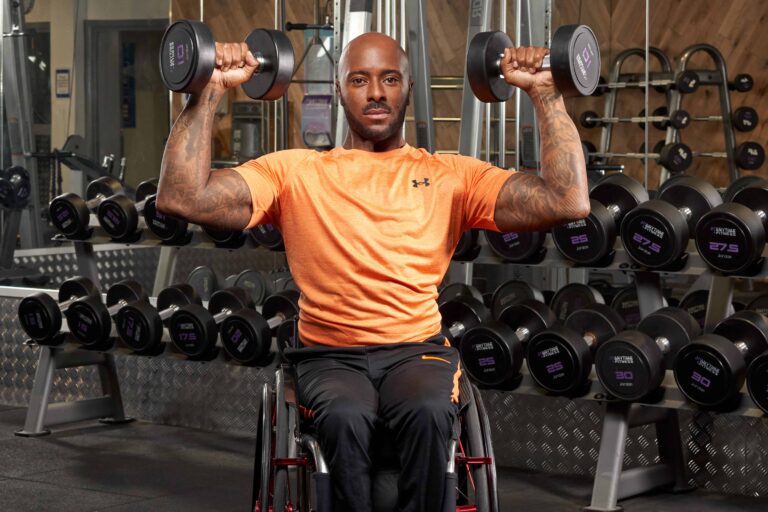 man in wheelchair starts overhead press in the gym
